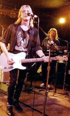 Mick Ronson (left) and Howard Helms (right rear) performing during a Mott the Hoople concert (Wikimedia Commons/Mike Bunyard)