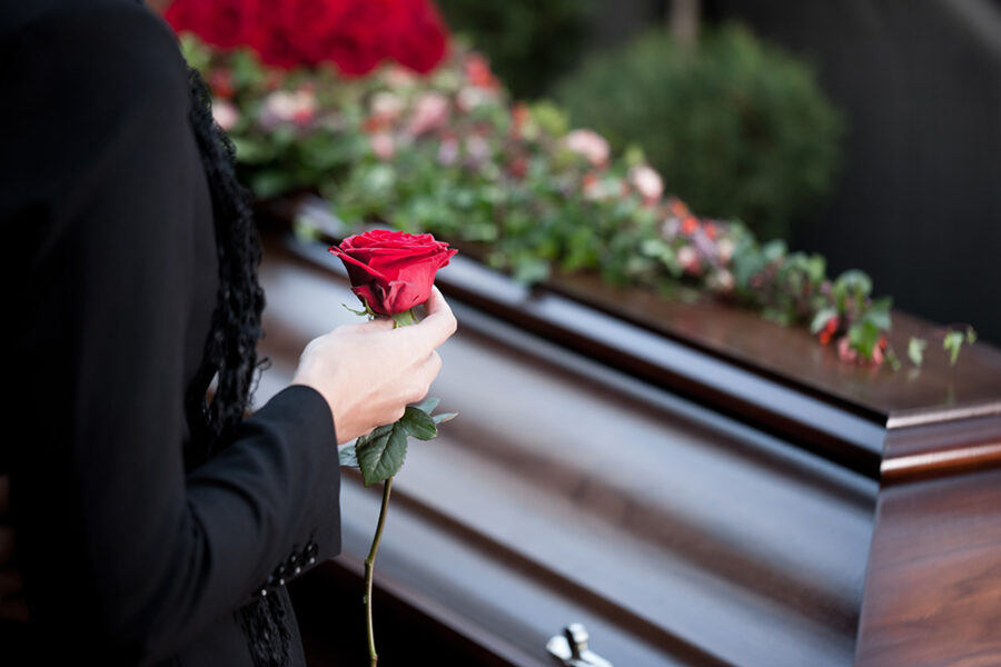 Grieving person at funeral holding rose